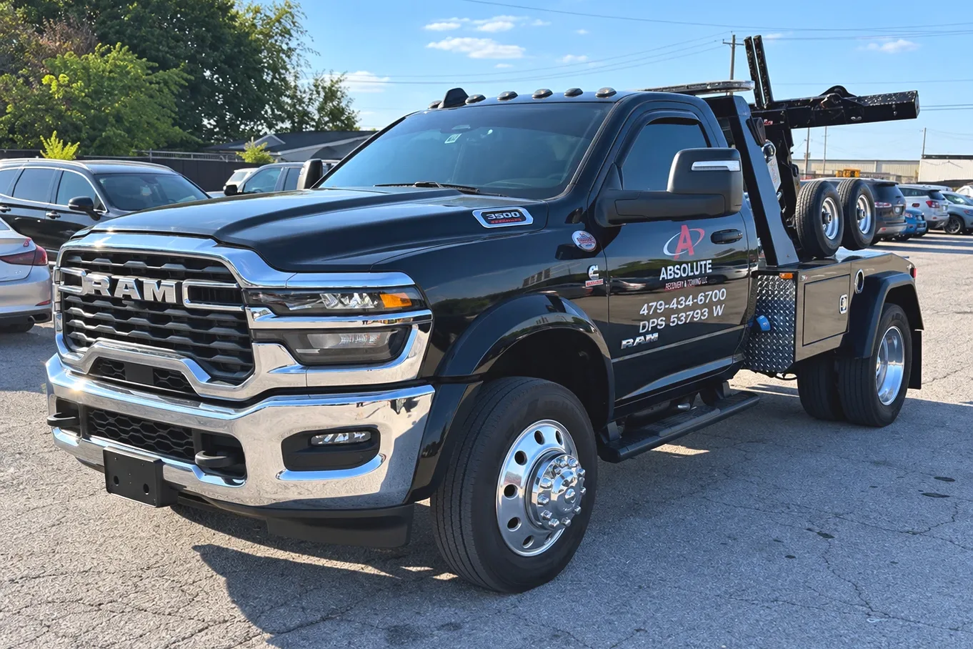 Black Ram 3500 wrecker lettered Absolute Recovery & Towing LLC with the phone number 479-434-6700, parked in a lot.
